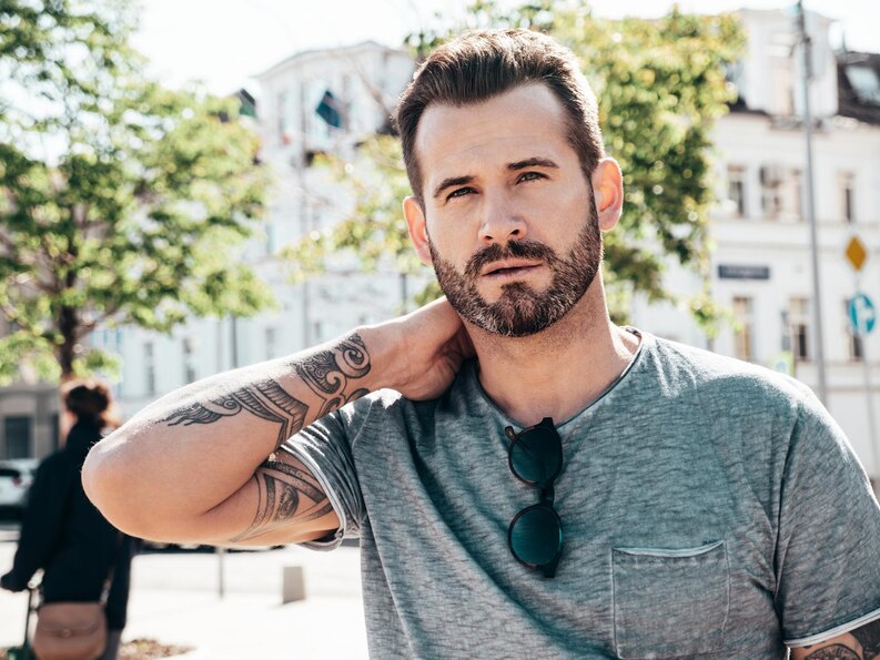 Man with a mid fade and textured top, smiling outdoors